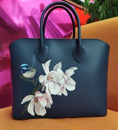 a handbag with flowers painted on it and a bird sitting on the flower branch