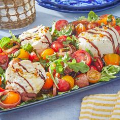 a salad with tomatoes, mozzarella and lettuce is on a blue platter