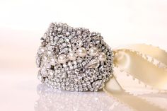 The Chloe bridal bracelet is a stunning and exquisite option to creates glamour into your bridal look. Just think sparkly Swarovski crystal romantic pearls tones creating a decadent bridal accent to your bridal attire * Cuff Features*Completely uniqueJust under 2 1/2'' wide at widest pointCustom fitted to you own wrist for perfect fitMade with swarovski crystals and swarpvski  rhinestone accentsClasp closure or ribbon tie your choiceLined in soft dove gray leatherCompletely hand sewnThis meticul Glamorous Sparkling Bracelets For Wedding, Glamorous Sparkling Bracelet For Wedding, Glamorous Cuff Bracelet For Wedding, Glamorous Wedding Cuff Bangle Bracelet, Exquisite White Wedding Bracelets, Luxury Rhinestone Wedding Bracelets, Glamorous Silver Cuff Bracelet For Wedding, Elegant Crystal Cuff Bracelet For Wedding, Glamorous Wedding Bracelets With Bling