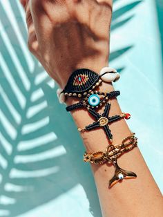 a woman's arm with several bracelets and an evil eye charm on it