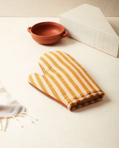 two oven mitts and a dish towel on a counter top next to a bowl