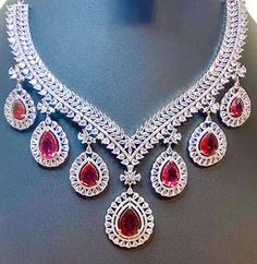 Experience the timeless elegance of our CZ American Diamond Necklace, featuring vibrant ruby pink colorstones. Perfectly complementing sarees, gowns or lehengas, this necklace adds a touch of glamour to any outfit. Complete the look with the included big earrings. Makes for a thoughtful and stylish gift. This jewellery set includes a necklace and matching earrings. Jewellery Care- Keep the jewellery dry, avoid contact with perfumes and water. Luxury Ruby Bridal Necklace, Elegant Chandbali Ruby Jewelry Sets, Elegant Ruby Bridal Necklace With Stone Work, Formal Ruby Chandbali Jewelry, Elegant Ruby Jewelry Sets For Reception, Elegant Heavy Ruby Bridal Necklace, Elegant Ruby Bridal Necklace For Reception, Formal Bollywood Necklace With American Diamond, Formal Ruby Jewelry With Stone Work