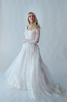 a woman in a white wedding dress posing for the camera with her hands on her hips