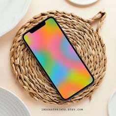 a cell phone sitting on top of a wicker basket next to plates and cups