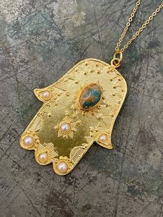 Hamsa Hand is very meaningful in many traditions. It's believed keep away from bad luck and negative things then turn them to Positive energy!! 21 ct gold plated brass. Turquoise and Pearl Length - Approx 83cm / top 6,5 x 5 cm Designed by our Turkish designer. Handcrafted with great care. Good Luck Pendant Jewelry With Natural Stones, Good Luck Pendant With Natural Stones, Spiritual Large Pendant Jewelry For Blessing, Large Spiritual Pendant Jewelry For Blessing, Traditional Turquoise Necklace With Large Pendant As Gift, Traditional Turquoise Necklace With Large Pendant, Turquoise Engraved Amulet Jewelry, Spiritual Turquoise Necklace Gift, Spiritual Turquoise Pendant Necklace