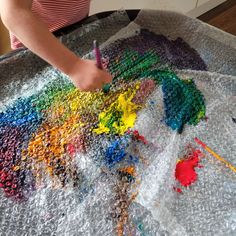 a child is painting with colored crayons on a large sheet of tin foil