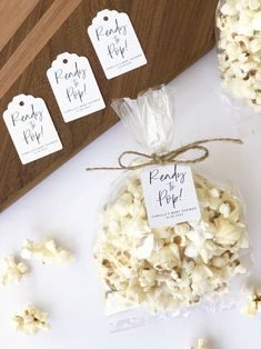 three bags of popcorn sitting next to each other on a white tablecloth with tags