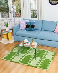 a living room with a blue couch and green rug