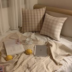 an open laptop computer sitting on top of a bed next to pillows and lemons