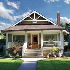 a small house with a porch and steps leading up to the front door on a sunny day