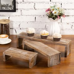 three wooden benches sitting on top of a wooden table next to a vase with flowers