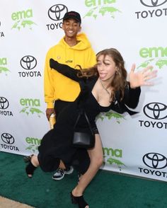 a man and woman posing on the green carpet