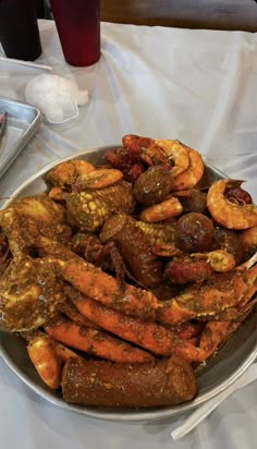 a plate full of cooked shrimp and other food items on a table with utensils