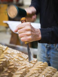 a man holding a knife in his right hand while working on some woodworking work