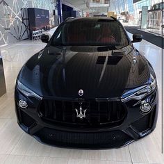 a maserato is parked in the middle of a shopping mall with its hood up