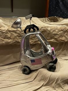 a silver toy car with an american flag on it's side sitting on top of a bed