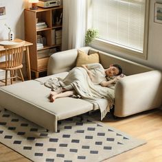 a woman laying on top of a couch under a blanket