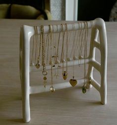 there is a white rack with many necklaces on it and a chair in the background