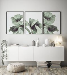 three paintings hanging on the wall above a white cabinet in a room with wooden flooring