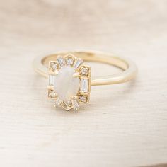 a gold ring with a white opal surrounded by diamonds