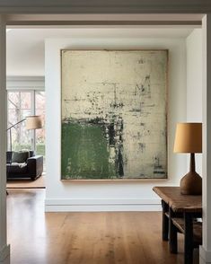 a large painting hanging on the wall in a living room next to a wooden table