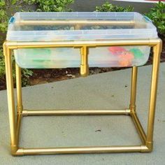 two plastic containers are sitting on a gold metal stand in front of some shrubbery