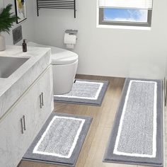 three bathroom rugs are placed on the floor in front of a toilet and sink