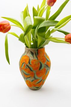 an orange and green vase with flowers in it