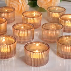 many small glass candles are sitting on a table