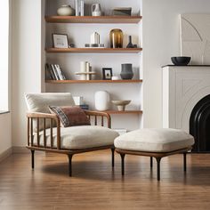 a chair and ottoman in front of a fireplace with bookshelves on the wall