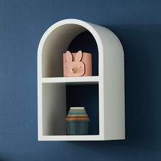 a white shelf with some items on it and a blue wall in the back ground