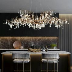 an elegant chandelier hangs from the ceiling above a kitchen island with stools