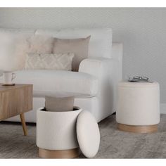 a living room with white furniture and pillows on the couch, coffee table and side tables