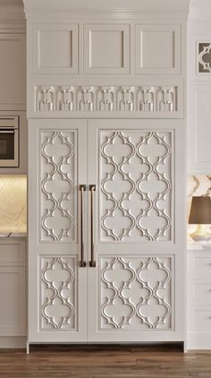 a kitchen with white cabinets and an ornate design on the door, along with a microwave oven