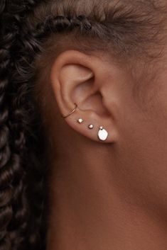 a woman wearing an ear piercing with two small white dots on the side of her ear