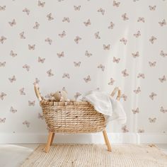 a basket with stuffed animals in it next to a wallpapered background that has butterflies on it