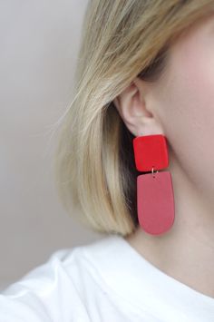 This is a pair of eye-catching statement earrings in a simple, geometric design- the top square is a bright cherry red color and the bottom rounded shape is a faded, dusty red color. These earrings have a minimalist design that is timeless, while the bright duo-tone colors add a modern vibe. These earrings are crafted using polymer clay, a surprisingly lightweight material that won't weigh you down. Each earring is carefully sanded and smoothed to ensure a well-made piece of jewelry that is comf Trendy Square Everyday Earrings, Modern Square Single Earring, Everyday Trendy Square Earrings, Red Drop Earrings For Everyday Wear, Red Jewelry With Matching Earrings For Everyday, Trendy Square Earrings As Gift, Modern Rectangular Earrings With Ear Wire, Trendy Red Drop Earrings, Bold Red Drop Earrings