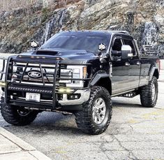 a large black truck parked in front of a mountain