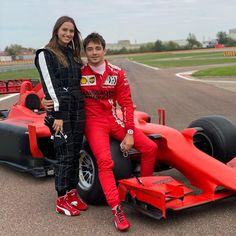 a man and woman standing next to a race car