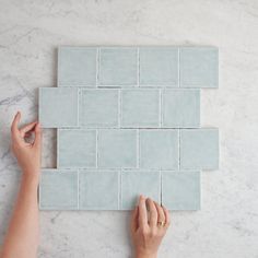 a person is placing tiles on the wall