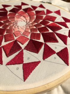 a close up of a red piece of cloth on a white surface with a wooden frame