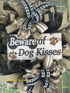 a sign that says beware of dog kisses on the front door with paw prints