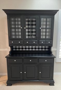 a black china cabinet with checkered glass doors