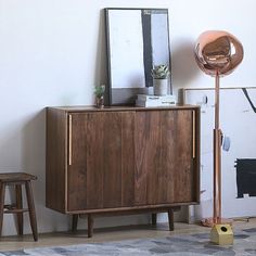 a wooden cabinet sitting in the corner of a room next to a mirror and stool