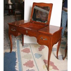 an antique desk with a mirror on it and a rug in front of the table