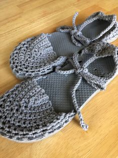 a pair of gray crocheted slippers sitting on top of a wooden floor