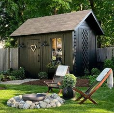 a backyard shed with lawn chairs and a fire pit in the grass next to it