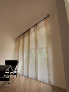 an empty chair in front of a window with vertical blinds on the outside and inside