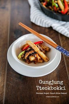 a white plate topped with stir fry and chopsticks