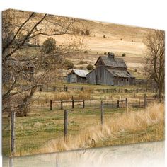 an old barn sits in the middle of a field with trees and grass around it